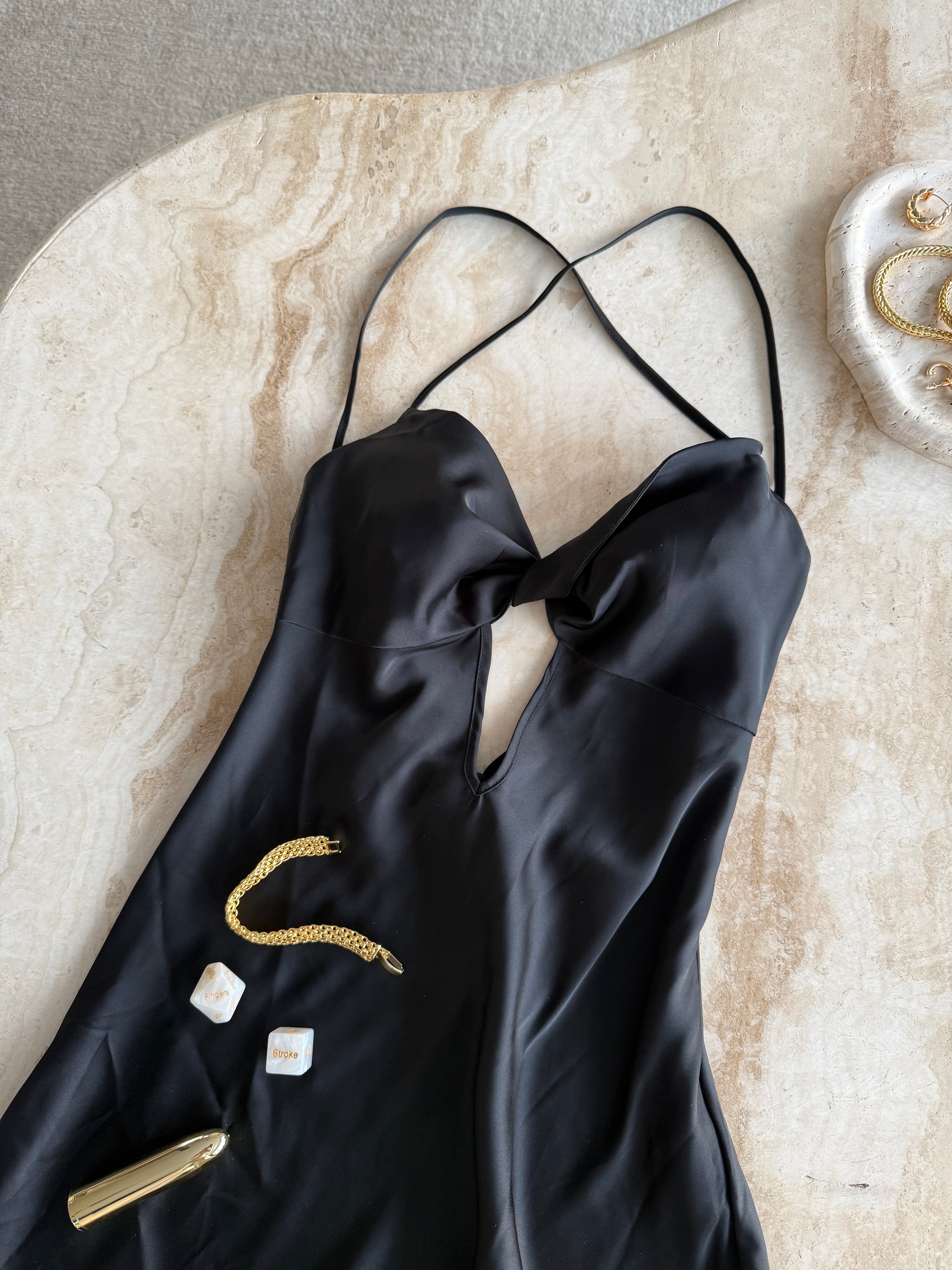 The Uma Satin Night Slip in black displayed on marble tabletop with gold jewelry and wellness accessory – elegant, sensual still life by SELF Seductions