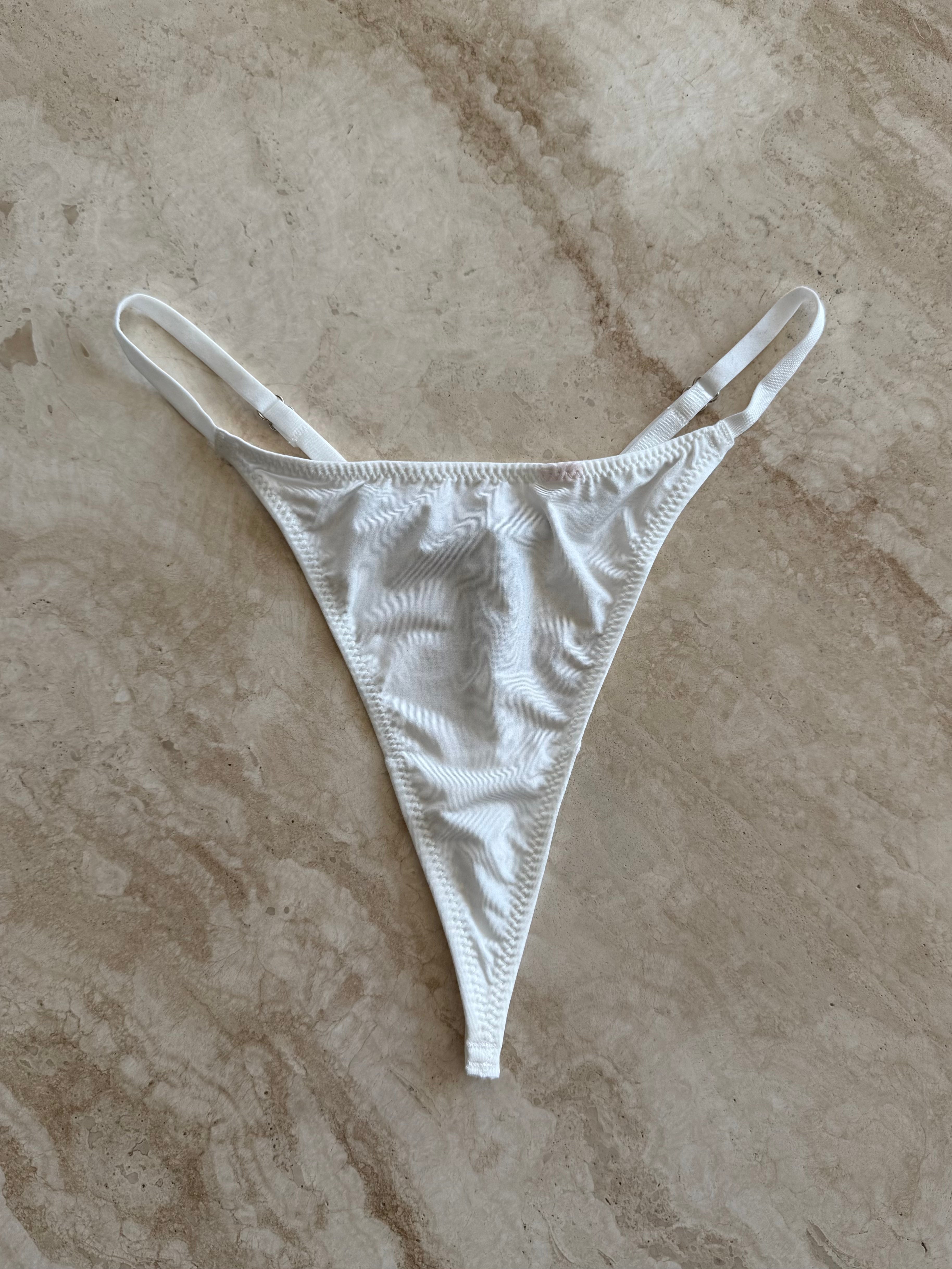 Front view of The Lilly Crystal V Thong in white – minimal silk-touch lingerie photographed on marble surface