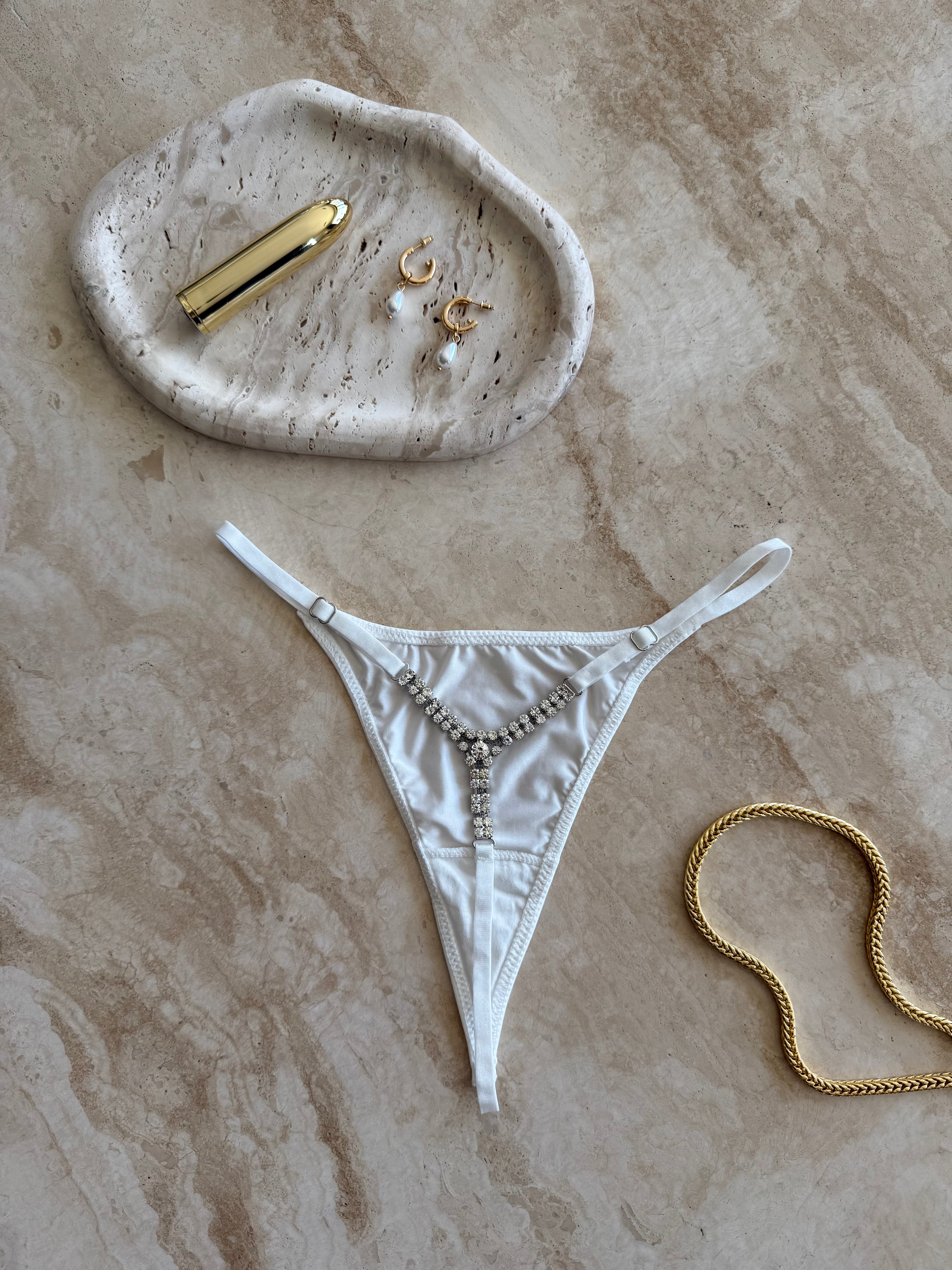 The Lilly Crystal V Thong in white styled with gold jewelry on marble surface – sensual flatlay by SELF Seductions