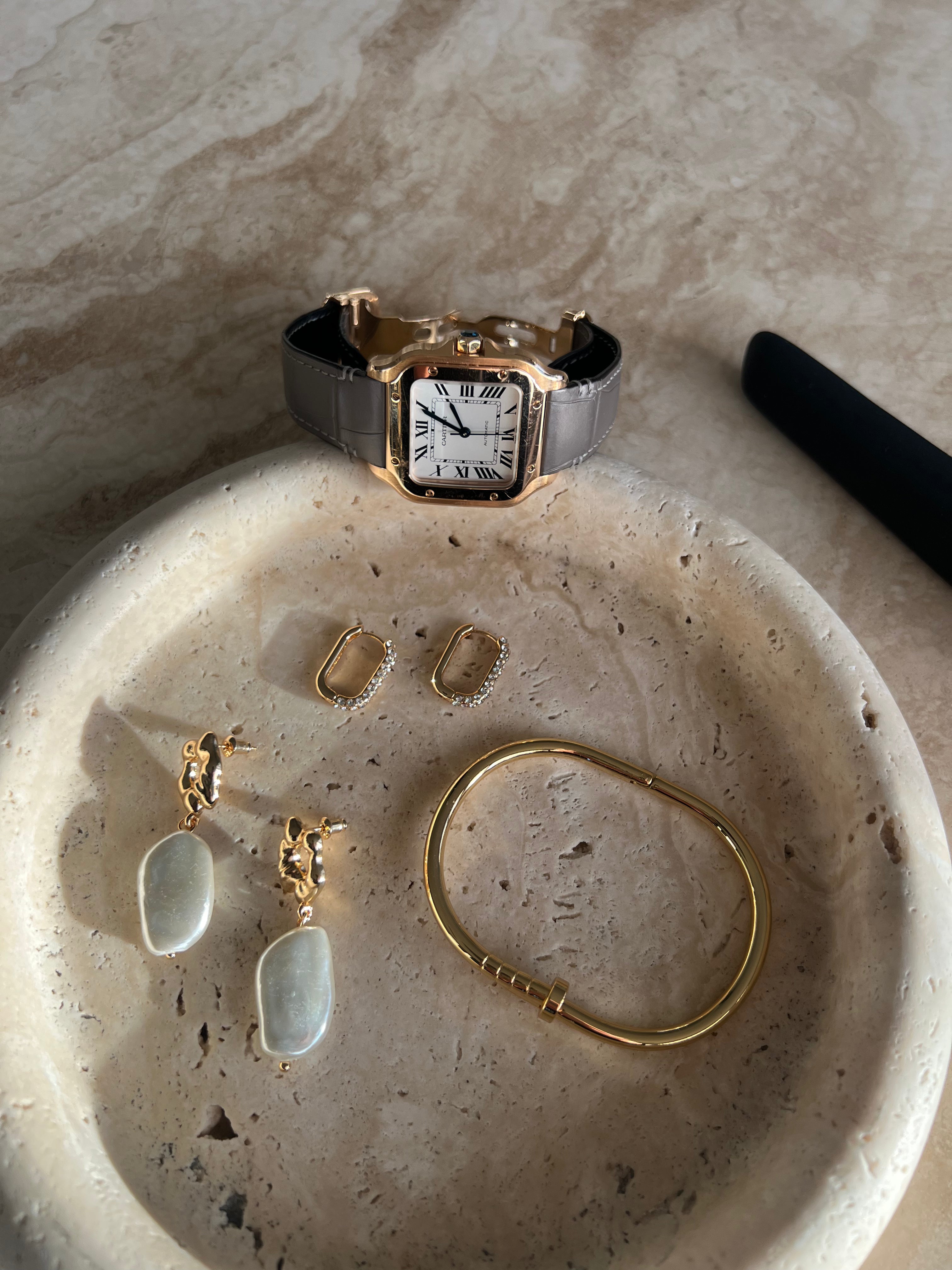 Close-up of The Allegra Gold-Plated Crystal Hoop Earrings with other gold jewelry in a stone dish by SELF Seductions