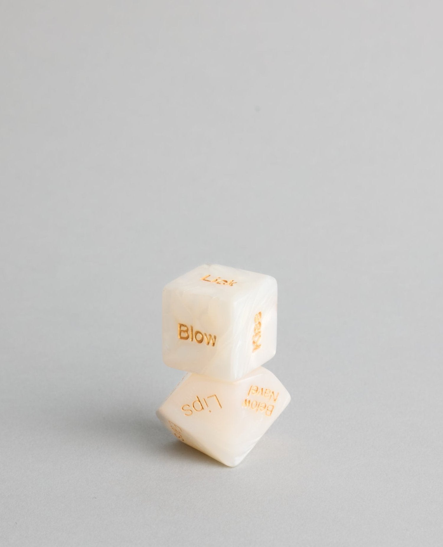 Close-up of pearl sensual dice with engraved gold text for intimate inspiration