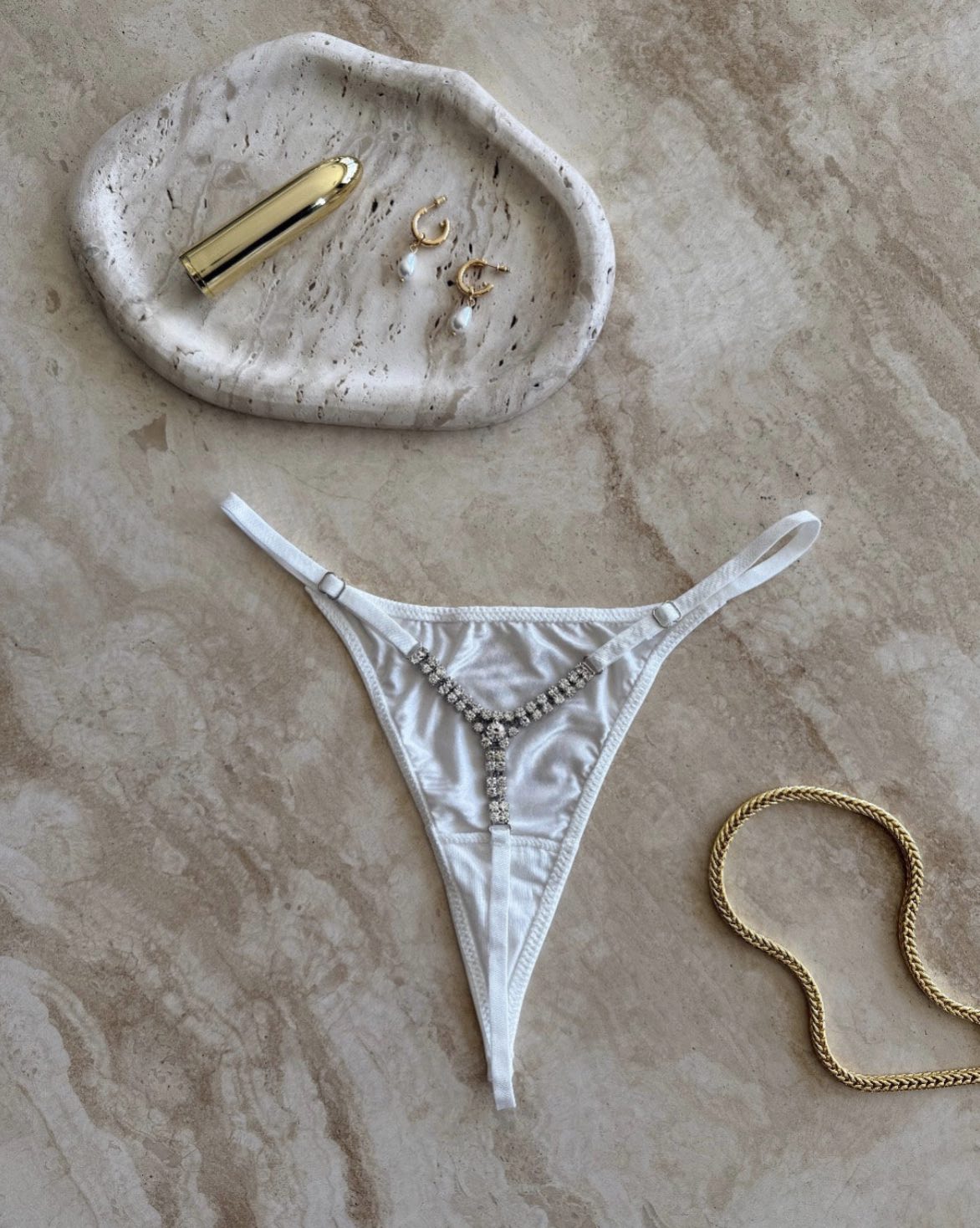 The Lilly Crystal V Thong in white styled with gold jewelry on marble surface – sensual flatlay by SELF Seductions