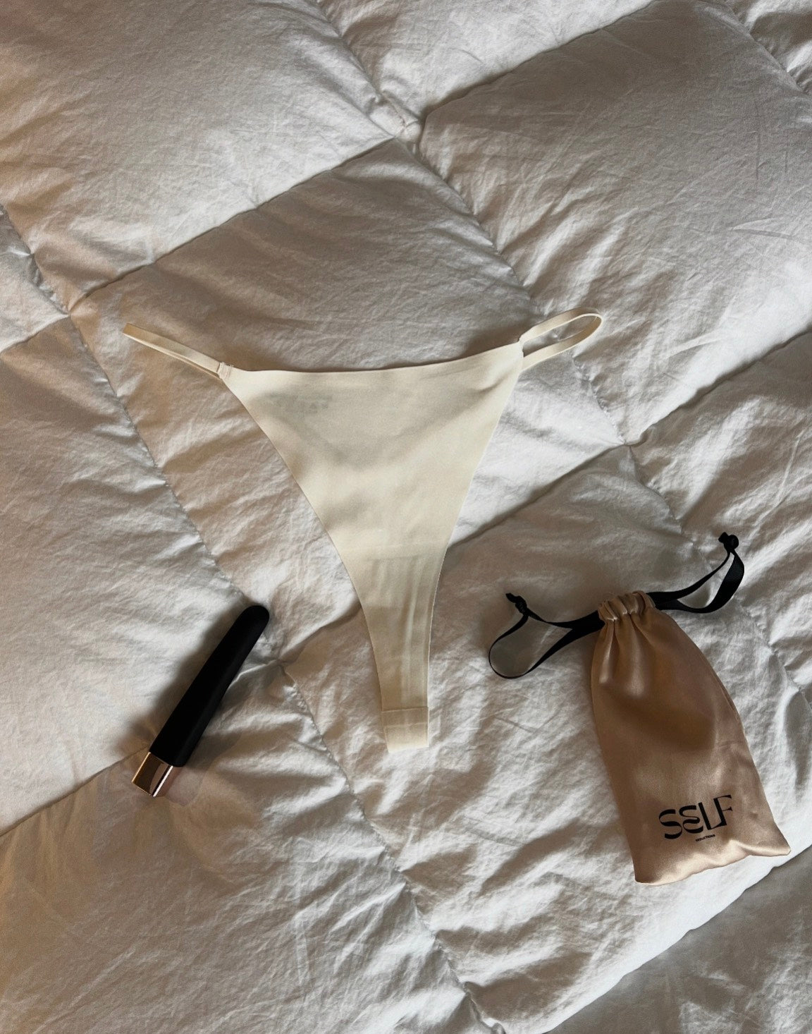 Kim Signature seamless soft yoga thong laying on bed in natural lig ht