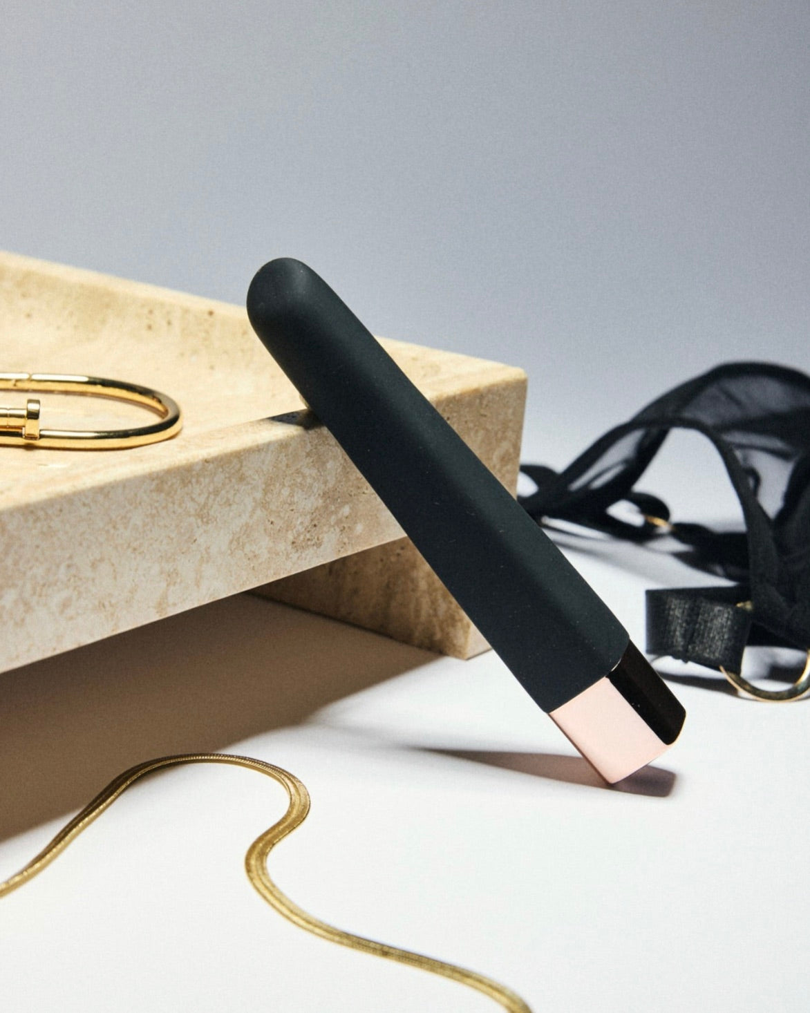 Black and rose gold bullet vibrator styled on marble with gold jewelry and black lingerie accents – modern luxury wellness aesthetic by SELF Seductions.