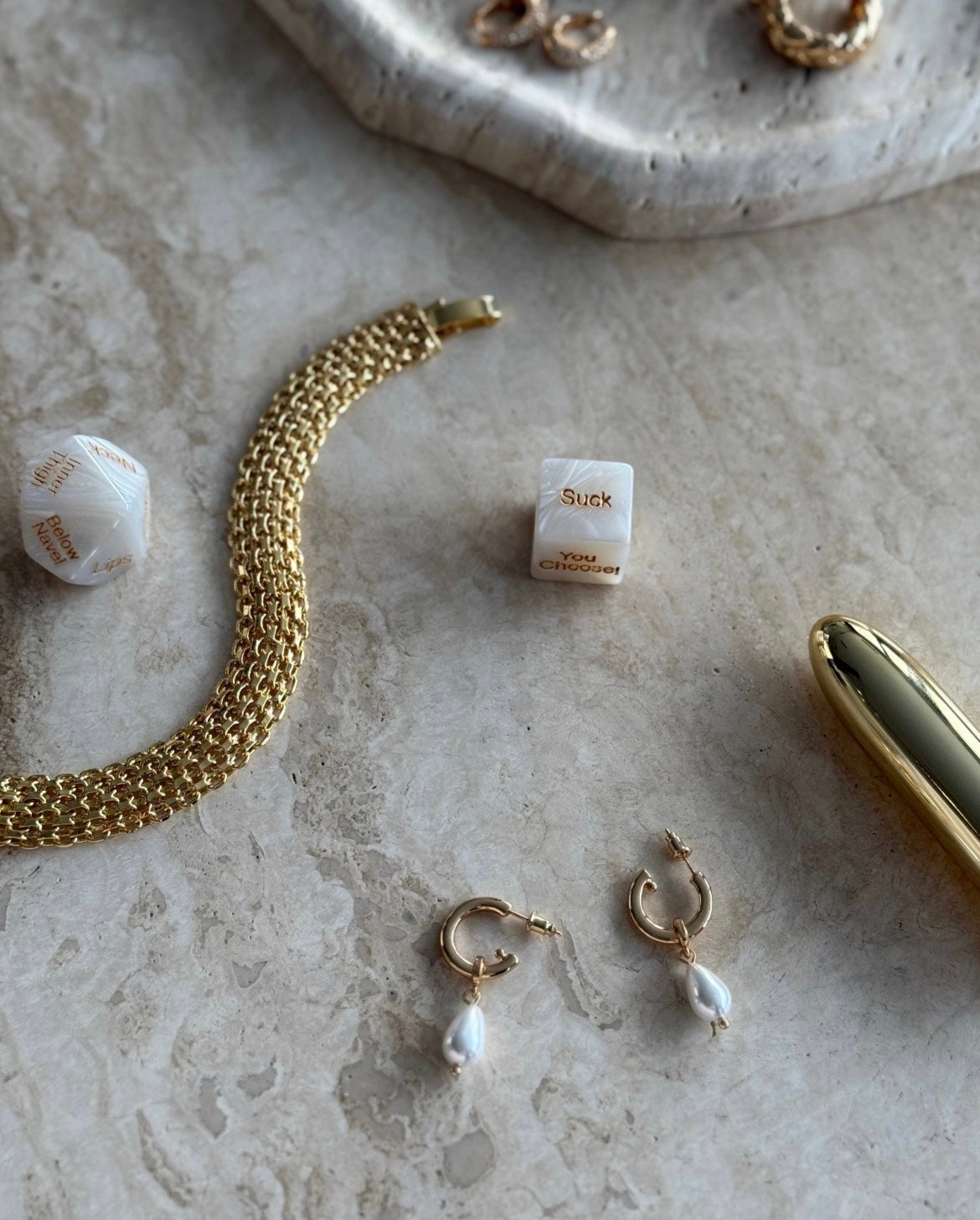 The Candace Drop Pearl Earrings in gold styled on beige marble with gold bracelet, sensual dice and wellness accessory – elegant SELF Seductions editorial.