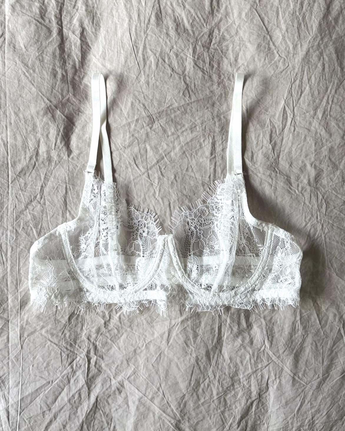 The Emma Soft Stretch Lace Bra in white – delicate lace lingerie styled on softly wrinkled linen bedding by SELF Seductions