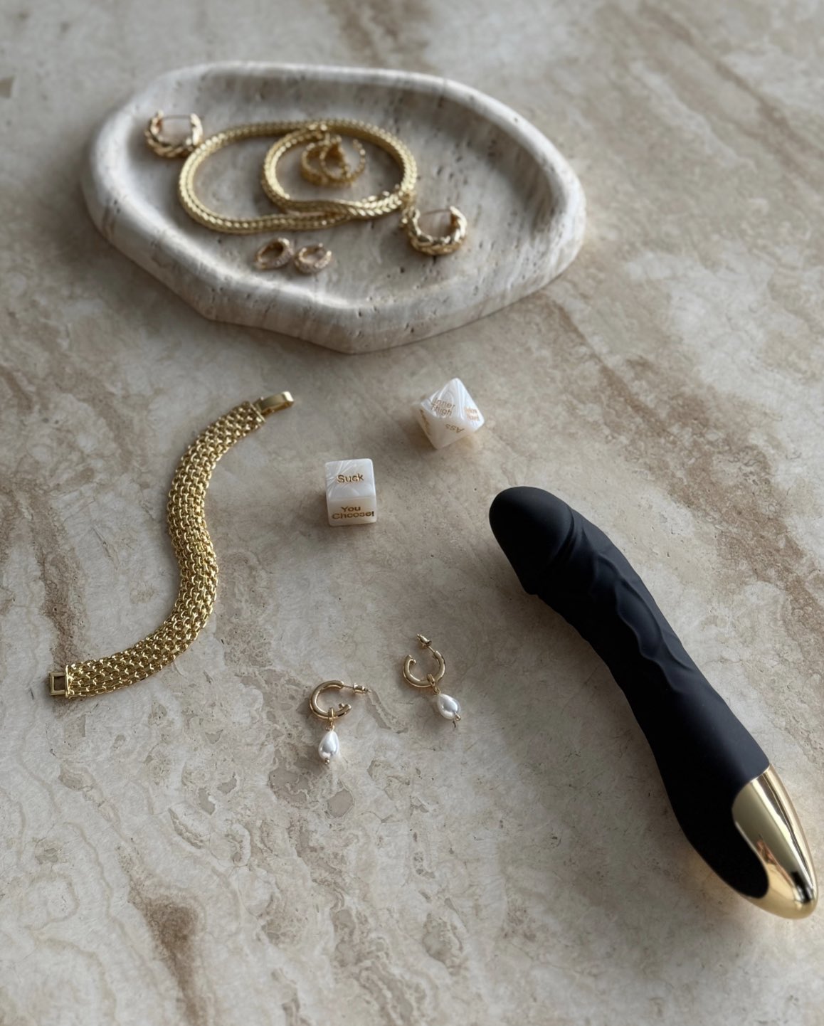 The Candace Drop Pearl Earrings in gold styled on beige marble surface beside gold jewelry and sensual dice by SELF Seductions